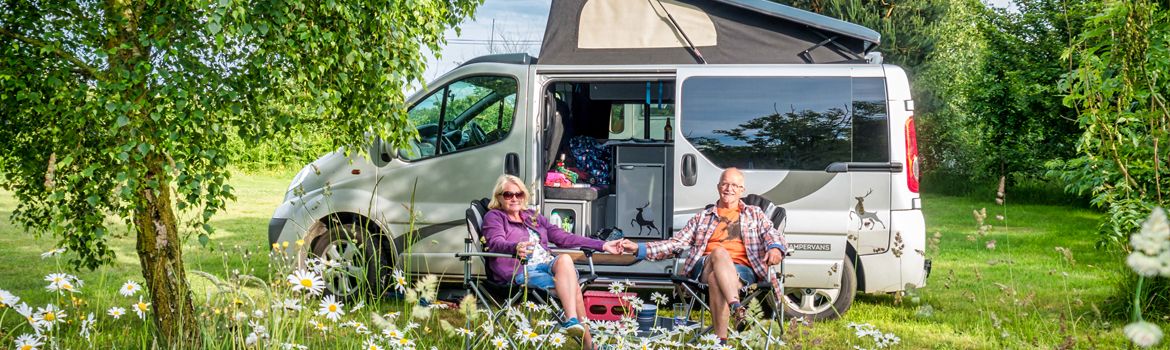 A couple sitting in front of a campervan