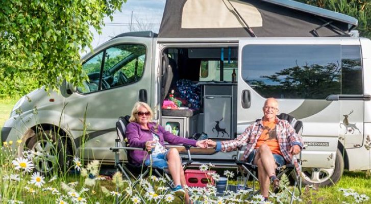 A couple sitting in front of a campervan